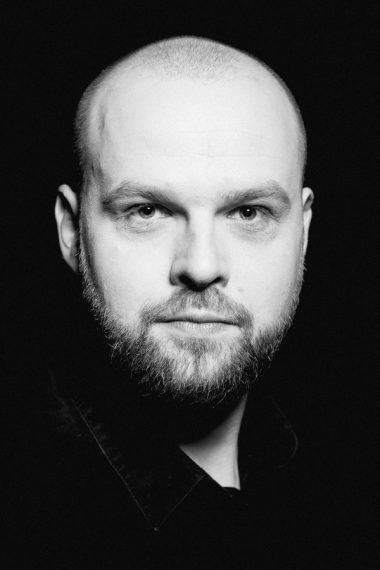 Mężczyzna na czarno-białej fotografii. Na zdjęciu Mariusz Adamski.