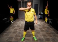 Trzech mężczyzn w różnych pozycjach w strojach sędziów piłkarskich