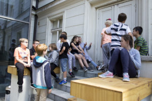 GRUPA MŁODZIEŻY NA BOCZNYCH SCHODACH PRZY WEJŚCIU DO TEATRU POLSKIEGO W POZNANIU. PROJEKT LATO W TEATRZE "MIĘDZY SŁOWAMI" 2017