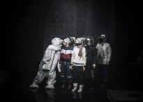 Aktorzy na tle Poznański Krzyży, koło nich postać przebrana w strój misia polarnego. Zdjęcie zbiorowe