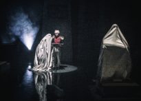 Aktor stojący przy pulpicie do nut, koło niego jak i przed nim