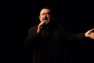 MĘZCZYZNA Z MIKROFONEM NA SCENIE. TADEUSZ DROZDA