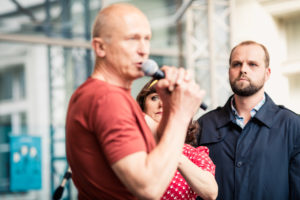 Aktor śpiewający do mikrofonu, w tle kobieta i mężczyzna