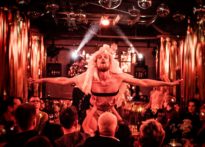 Aktor unoszony przez aktorów znajdujacych się wśród publiczności ubrany w bieliznę i welon. Na zdjęciu Maciej Pesta