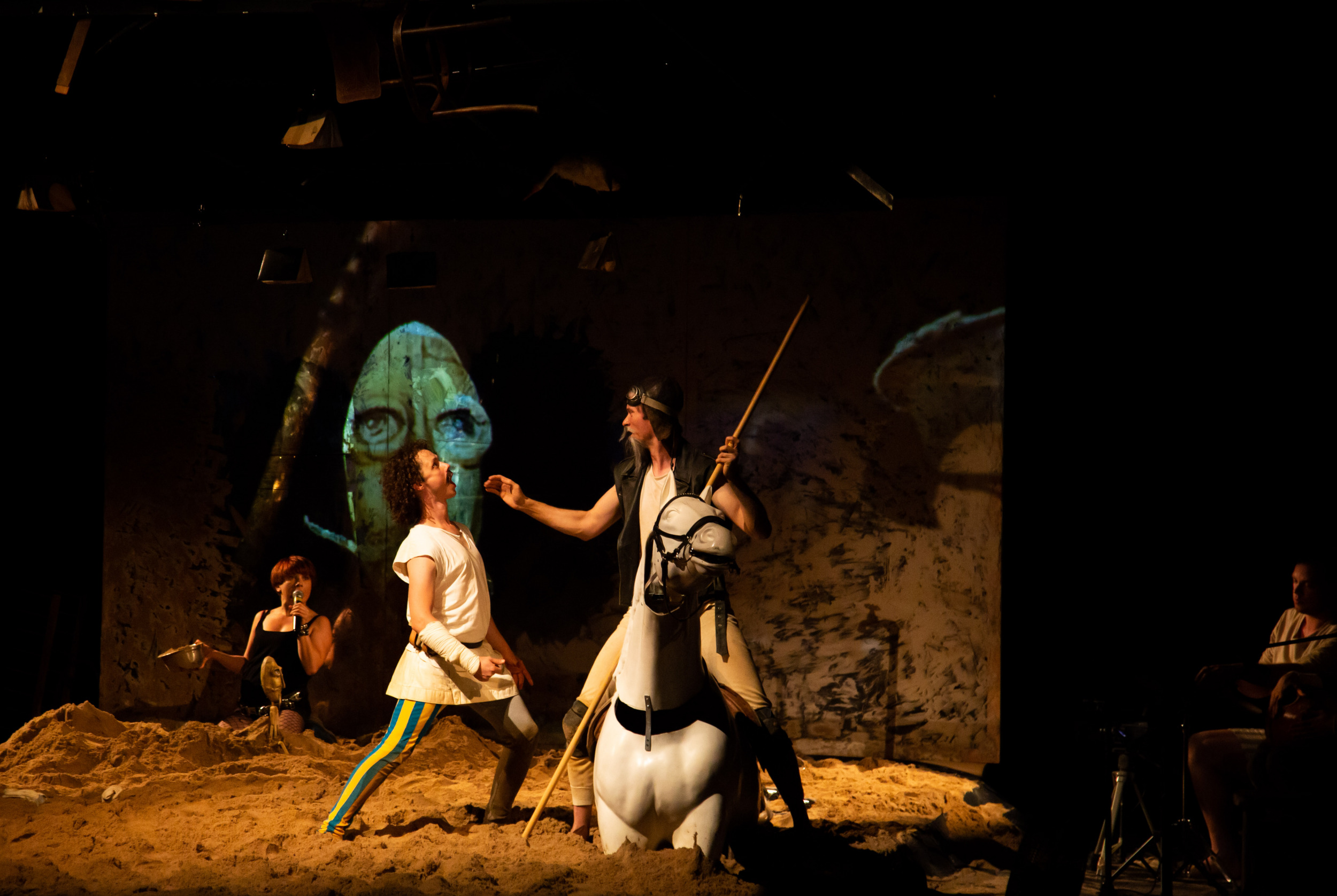 TROJE AKTORÓW NA SCENIE WYSYPANEJ PIASKIEM. NA PIERWSZYM PLANIE DWÓCH MĘŻCZYZN - JEDEN NA KONIUZDJĘCIE ILUSTRACYJNE ZE SPEKTAKLU DON KICHOT W RAMACH 9. FESTIWALU KONTEKSTY