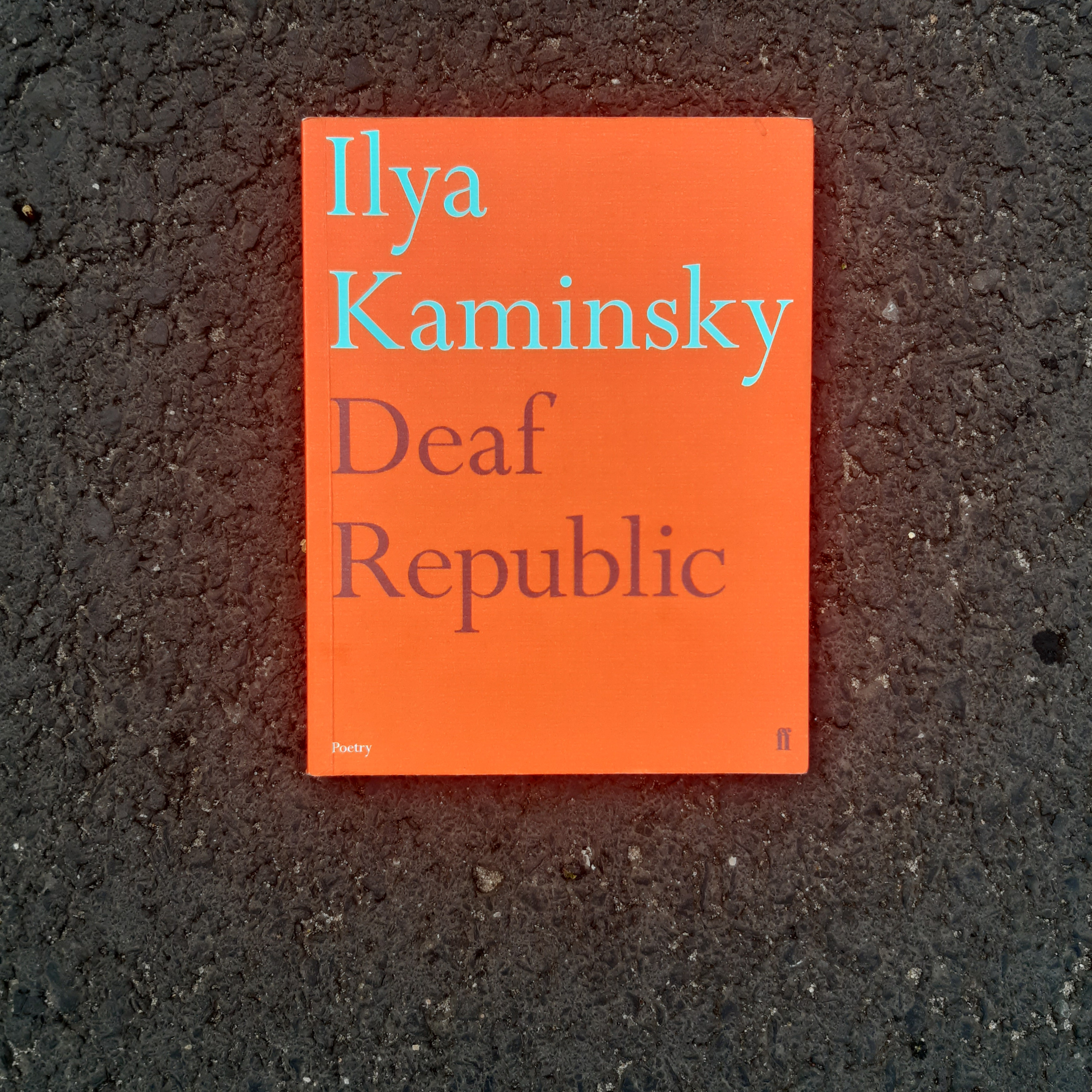 Pomarańczowa okładka książki z napisem "Ilya Kaminsky Deaf Republic".